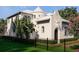 Elegant cream-colored two-story home with a turret, lush landscaping, and dark metal fencing at 5009 W Spring Lake Dr, Tampa, FL 33629