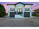 Charming two-story home featuring a unique aqua and white color scheme, double garages, and elevated entry with black railings at 3230 Azalea Drive # Lot 13, Hernando Beach, FL 34607