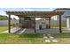 Covered outdoor kitchen and bar area with TV and pavers under pergola at 9358 Rally Spring Loop, Wesley Chapel, FL 33545