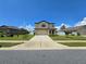 Two-story house with a tan exterior, two-car garage, and a well-maintained lawn at 6949 Crested Orchid Dr, Brooksville, FL 34602