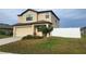 Two-story house with a tan exterior, two-car garage, and a white fence at 6949 Crested Orchid Dr, Brooksville, FL 34602