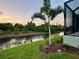Peaceful backyard view of canal, lush landscaping, and screened patio at 156 Haddock Dr, Rotonda West, FL 33947