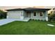 Newly built home with light green exterior, two car garage, and a manicured lawn at 156 Haddock Dr, Rotonda West, FL 33947