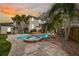 Exterior shot showcasing a pool, spa, and landscaping against a sunset backdrop at 5002 W Homer Ave, Tampa, FL 33629