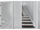Bright staircase with wooden treads and white risers, adjacent to an open doorway revealing a modern, marble-floored bathroom at 5002 W Homer Ave, Tampa, FL 33629