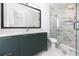 Elegant bathroom with marble shower, dark green vanity, and a large mirror at 1308 E Columbus Dr # 1, Tampa, FL 33605
