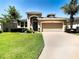 Tan one-story house with lush green lawn, attached garage, and driveway at 29405 Cochiti Lake Dr, San Antonio, FL 33576