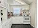 Simple kitchen with white cabinets, gray countertops and a white stove at 3615 Wellington Dr, Holiday, FL 34691