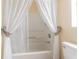 Clean bathroom with tub shower and white sheer curtains at 37607 Neukom Ave, Zephyrhills, FL 33541