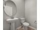 Modern powder room with pedestal sink, round mirror and neutral color palette at 3484 Timber Crossing Ave, Brandon, FL 33511