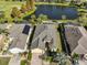 Aerial view of a home with a well-manicured lawn, solar panels, and a serene pond at 1007 Emerald Dunes Dr, Sun City Center, FL 33573