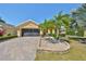 Charming home showcasing a paved driveway, well-manicured lawn, lush landscaping, and mature palm trees at 1007 Emerald Dunes Dr, Sun City Center, FL 33573