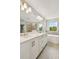 Bright bathroom featuring double sinks, white cabinets, and a soaking tub with exterior views at 7201 S De Soto St, Tampa, FL 33616