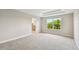 Bright bedroom featuring neutral walls, carpeted floor, tray ceiling, and a window view of lush greenery at 7201 S De Soto St, Tampa, FL 33616