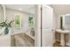 Inviting entryway with light wood floors, white door, and a view of a powder room, offering convenience and style at 7201 S De Soto St, Tampa, FL 33616