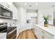Modern kitchen with stainless steel appliances, white cabinetry, quartz countertops, and wood-look floors at 7201 S De Soto St, Tampa, FL 33616