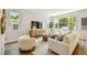 Sunlit living room features large windows, stylish seating, and a rustic wooden table, perfect for a relaxing ambiance at 7201 S De Soto St, Tampa, FL 33616