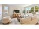 Bright living room with a tan sofa, white chairs, a wooden cabinet, and large windows for natural light at 7201 S De Soto St, Tampa, FL 33616