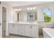 Bright bathroom featuring a large mirror, double sink vanity, soaking tub, and natural light at 7201 S De Soto St, Tampa, FL 33616