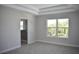 Bright bedroom with tray ceiling, neutral carpet, ensuite bathroom and large window with leafy views at 7205 S De Soto St, Tampa, FL 33616