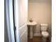 Half bathroom with a pedestal sink, toilet, and wood-look floors at 7205 S De Soto St, Tampa, FL 33616