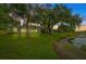 Backyard with lake view, lush lawn, and mature trees at dusk at 11647 Fox Creek Dr, Tampa, FL 33635