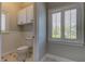 White toilet and wainscoting in small bathroom with white cabinets at 7510 N Mobley Rd, Odessa, FL 33556