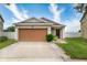 Cute one-story house with a brown garage door at 14415 Dunrobin Dr, Wimauma, FL 33598