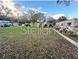 Vacant lot with overgrown grass and distant homes at 6902 Rhode Island Dr, Tampa, FL 33619