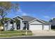 Charming single-story home featuring a three-car garage, manicured lawn, and beautiful landscaping at 28330 Openfield Loop, Wesley Chapel, FL 33543