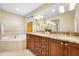 Bathroom featuring double sinks with granite counters, wood cabinets, and neutral tiling at 5510 E Longboat Blvd, Tampa, FL 33615