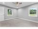 This bedroom features neutral walls, a ceiling fan, base molding, and two windows for natural light at 11734 Orange Ct, Dade City, FL 33525