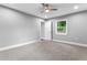 This bedroom features neutral walls, a ceiling fan, base molding, a window, and an open door at 11734 Orange Ct, Dade City, FL 33525