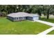 Aerial view of a one-story gray home with stone accents, attached garage, and a green lawn at 11734 Orange Ct, Dade City, FL 33525
