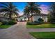 Luxury home with palm trees, brick driveway, and landscaped yard at dusk at 15908 Castle Park Ter, Lakewood Ranch, FL 34202