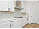 Modern kitchen features white cabinets, a stainless steel range hood, and geometric backsplash at 8328 Golden Beach Ct, Parrish, FL 34219