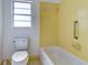 Bright bathroom with yellow tile, a bathtub, and toilet at 1810 Haverford Ave, Sun City Center, FL 33573