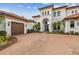 Two-car garage and grand entrance of luxury home with brick driveway at 12310 Stonelake Ranch Blvd, Thonotosassa, FL 33592
