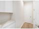 Well-lit mud room area with white cabinets, a countertop, and hardwood flooring leading to a closed door at 33797 Ocean Spray Ln, Wesley Chapel, FL 33543