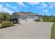 Three-car garage with a large concrete driveway and landscaping at 6218 Bridleford Dr, Wesley Chapel, FL 33545