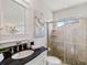 Bathroom with a tiled shower, vanity with black countertop, and a decorative painting at 33724 Americana Ave, Dade City, FL 33525