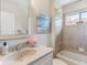 Well-lit bathroom featuring a tile shower, neutral countertop, and decorative floral arrangement at 33724 Americana Ave, Dade City, FL 33525