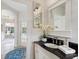 Charming powder room featuring a vanity with black countertop, white cabinets, and stylish mirror at 33724 Americana Ave, Dade City, FL 33525