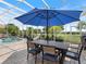 Outdoor dining area with seating for six, located next to the pool and lush landscaping at 33724 Americana Ave, Dade City, FL 33525