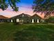 Inviting home exterior with lush lawn, mature trees, manicured landscaping, and dusk sky at 33724 Americana Ave, Dade City, FL 33525