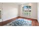 Bright living room features a decorative rug, hardwood floors, and a large window with plantation shutters at 33724 Americana Ave, Dade City, FL 33525