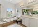 Luxurious bathroom features a soaking tub, a vanity area, and natural light from a window, creating a spa-like retreat at 33724 Americana Ave, Dade City, FL 33525