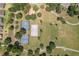 Aerial view of a community park with tennis courts, a basketball court, an open recreation area, and walking paths at 33724 Americana Ave, Dade City, FL 33525