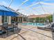 Screened-in pool area with outdoor dining space, lounge chairs, lush landscaping, and a sparkling pool at 33724 Americana Ave, Dade City, FL 33525