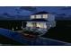 Contemporary two-story home with covered lanai and an expansive waterfront pool and dock at night at 5243 Wishing Arch Dr, Apollo Beach, FL 33572
